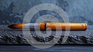 A bamboo calligraphy brush resting on a textured surface.