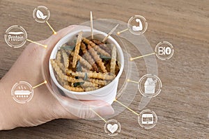 Bamboo Caterpillar insects for eating as food in disposable cup with icon media nutrition concept on wood background. Bamboo worm