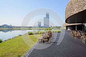 Bamboo chair and tables on lakeside asphalted way in summer morning