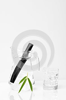 Bamboo charcoal water filter stick, green leaf and glass of water. Natural bamboo charcoal is a powerful purifier which refreshes