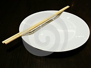 Bamboo chopsticks on white plate and black background