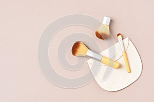 Bamboo cosmetic brushes on beige background, copy space