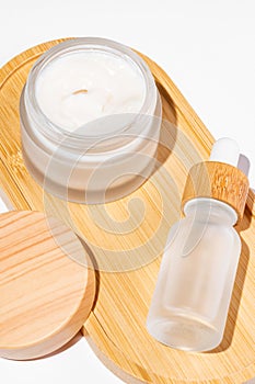 Bamboo cream jar and dropper bottle with face oil on white background. Cosmetic container mockups. Background for branding and