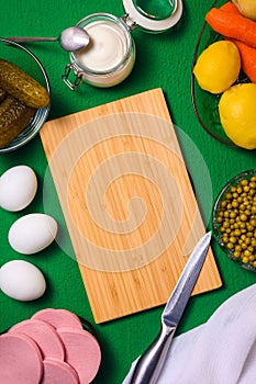 bamboo cutting board and ingredients for making russian olivier salad