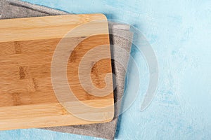 Bamboo cutting Board and linen towel on blue background