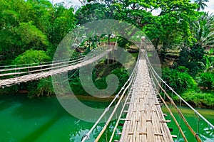 Bamboo hanging bridge over river photo