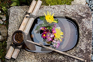 Bamboo ladle on a stone basin filled with a flower arrangement in Kyoto Japan