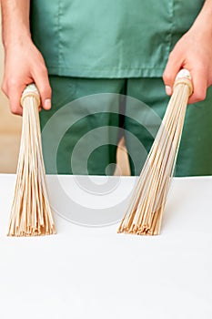 Bamboo massage brooms in hands