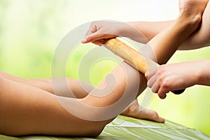 Bamboo massage on female leg.