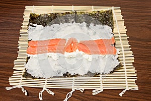On a bamboo Mat Nori leaf with rice, cheese, salmon