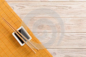 Bamboo mat and soy sauce with sushi chopsticks on wooden table. Top view with copy space background for sushi. Flat lay