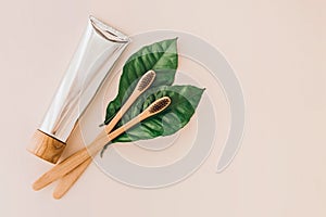 Bamboo natural toothbrushes, toothpaste and fresh leaves on pale background. Zero waste and plastic free concept