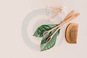 Bamboo natural toothbrushes, toothpaste and fresh leaves on pale background. Zero waste and plastic free concept