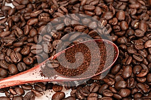 Bamboo spoon with ground coffee, lies on roasted coffee beans, close-up, isolated on a white background