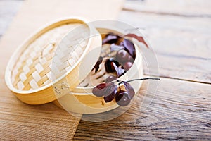 a bamboo steamer filled with grapes on a wooden table