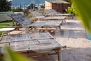 Bamboo sunbeds lined up by the pool, a hint of greenery in the foreground, serene holiday vibe for relaxation.