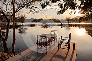 Bamboo table and chairs with lake view on waterfront at sunset