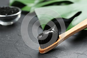 Bamboo toothbrush with charcoal paste on stone table, closeup. Space for text