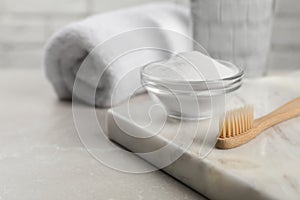 Bamboo toothbrush and glass bowl of baking soda on light table, space for text