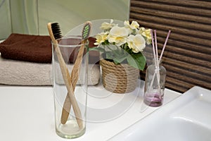 Bamboo toothbrush in glass stand with towel in Zero waste bathroom. Plastic free beauty essentials. eco friendly home