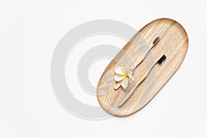 Bamboo toothbrush on a table with copy space on a white background. Styled composition of flat lay with tropical flowers