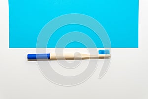 Bamboo toothbrush on a white and blue background Ecological and sustainable product concept.