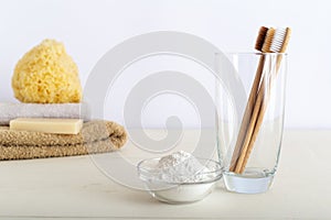 Bamboo toothbrushes in glass, dentifrice tooth powder on white background witn natural bath products. Biodegradable natural bamboo photo