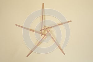Bamboo wooden sticks demonstrating a pentagram reciprocal frame structure, on beige background photo