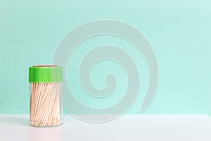 Bamboo or wooden toothpick in a plastic box on green background. Concept, Free space for text