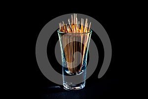 bamboo wooden toothpicks in glass jar, wine glass. in bucket. toothpicks on black background. front view toothpicks, dropped from