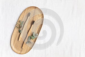 Bambool toothbrush and leaves of eucalyptus on a wooden plate.