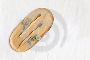 Bambool toothbrush and leaves of eucalyptus on a wooden plate.