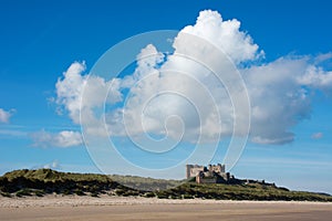 Bamburgh Castle from a distance England with clear blue sky and bright clouds