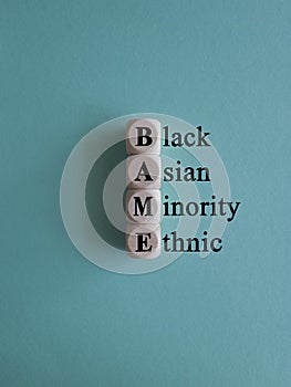 BAME symbol. Abbreviation BAME, black, asian and minority ethnic on wooden cubes. Beautiful blue background photo
