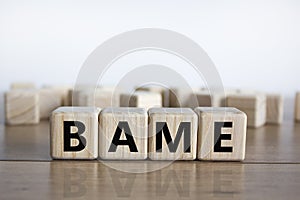 BAME symbol. Abbreviation BAME, black, asian and minority ethnic on wooden cubes. Beautiful wooden table, white background. Copy photo