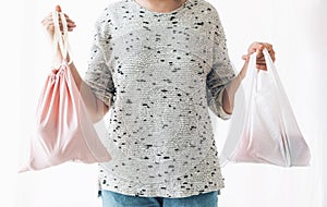 Ban single use plastic. Zero Waste shopping concept. Woman holding in one hand groceries in reusable eco bag and in other