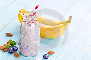 Banana and blueberry diet smoothie with yogurt or milk, almonds and fresh berries in glass bottles