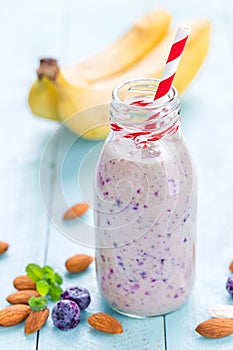 Banana and blueberry diet smoothie with yogurt or milk, almonds and fresh berries in glass bottles