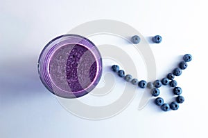 banana and blueberry smoothie in a glass cup with a smiling face of blueberries