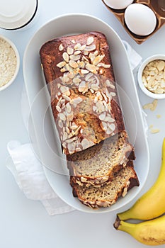 Banana bread with almonds on a white plate on a white background. Ingredients for home baking background