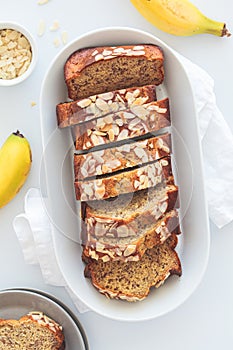 Banana bread with almonds on a white plate on a white background. Ingredients for home baking background