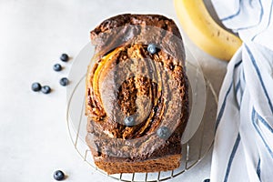 Banana bread with blueberries on a cooling rack on a gray background. Overhead view