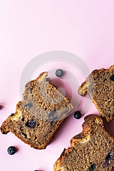 Banana bread slices with blueberries on a pink background. Flat lay and top view