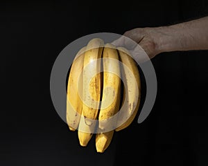 Banana bunch in male hand in dark