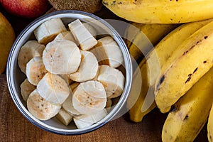 Banana bunch, sliced bananas in bowl and on wooden board