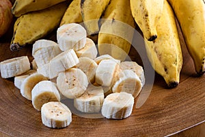 Banana bunch, sliced bananas in bowl and on wooden board