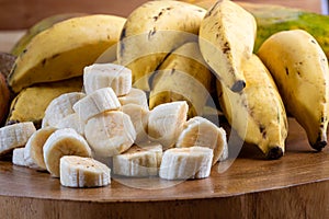 Banana bunch, sliced bananas in bowl and on wooden board