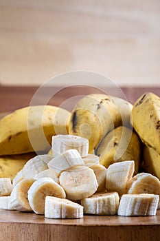 Banana bunch, sliced bananas in bowl and on wooden board