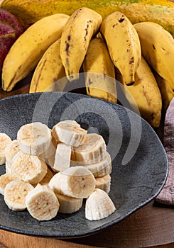 Banana bunch, sliced bananas in bowl and on wooden board