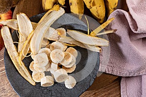 Banana bunch, sliced bananas in bowl and on wooden board